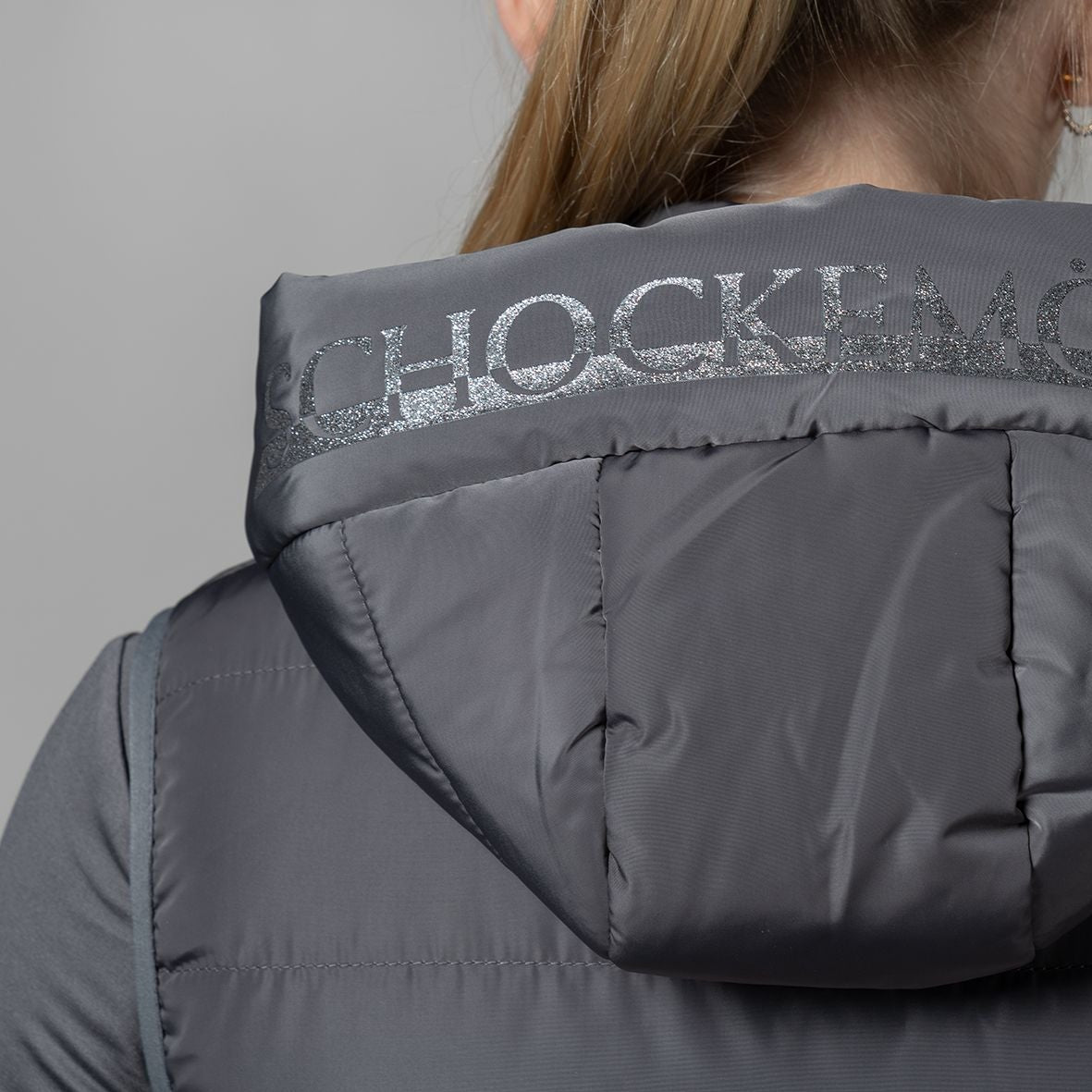 Schockemöhle Sports SPMalea Style Womens Vest - Gray aka Dusty Chocolate, detail back view on woman, of hood | Malvern Saddlery