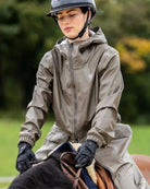 Horse Pilot Long Raintech Coat - Coffee brown - worn by woman riding horse outdoors | Women's Outerwear | Malvern Saddlery