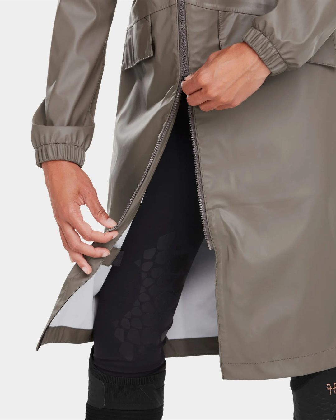 Horse Pilot Long Raintech Coat - Coffee brown - bottom 2-way zipper detail - worn by woman against white background | Women's Outerwear | Malvern Saddlery