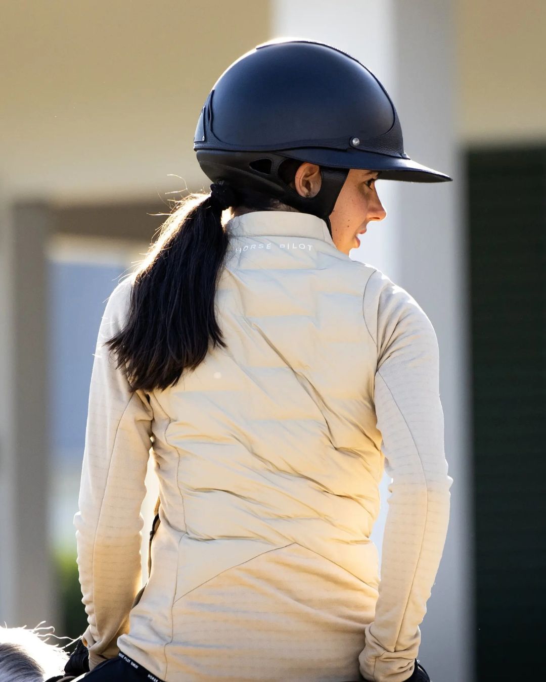Horse Pilot Women's Storm Jacket - Latte, back view shown on rider | Equestrian Outerwear | Malvern Saddlery