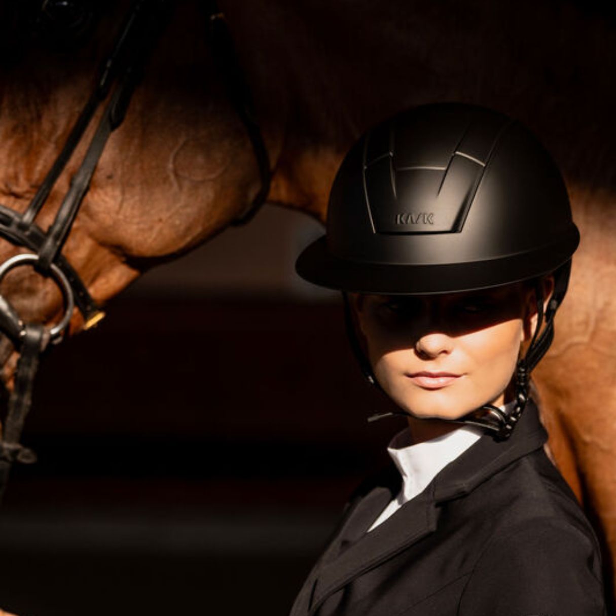 KASK Kooki Lady Equestrian Helmet - Black Shadow - Hunter style; close up shown on woman with horse behind her | Wide Brim Helmets | Malvern Saddlery