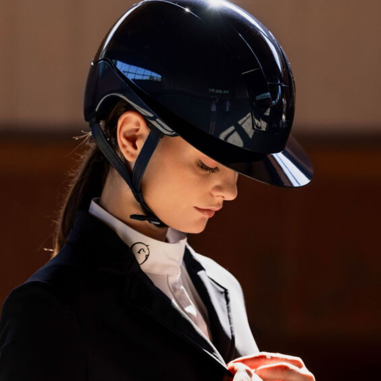 KASK Kooki Lady Equestrian Helmet - Navy shine; shown on woman wearing show coat, blurred brown background | Wide Brim Helmets | Malvern Saddlery