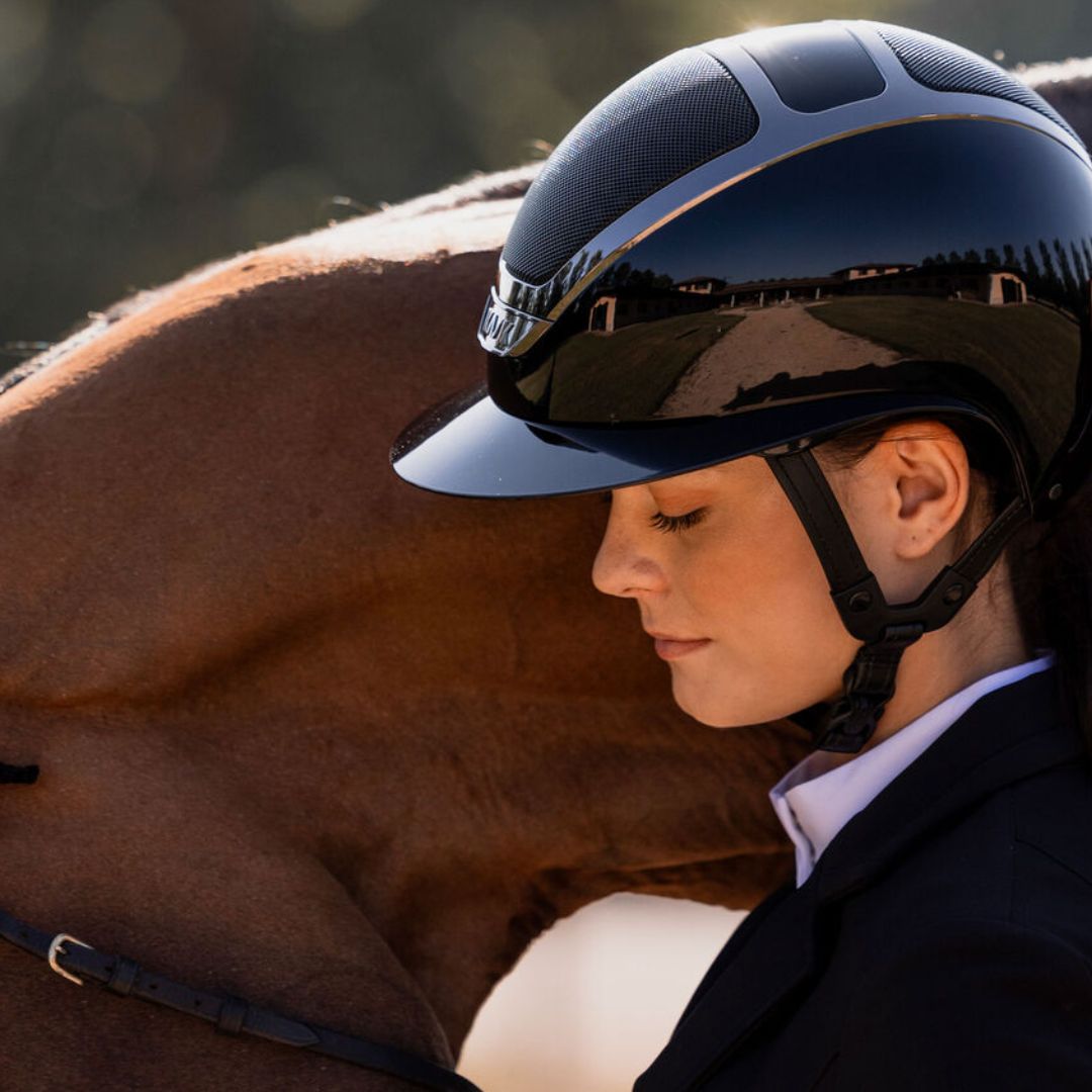KASK Star Lady Pure Shine Equestrian Helmet - Atlantic Blue; lifestyle close up shown on woman with brown horse | English Riding Helmets | Malvern Saddlery