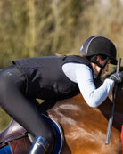 Person riding a horse in equestrian attire wearing Charles Owen Eclipse Back Protector with a blurred natural background | Malvern Saddlery