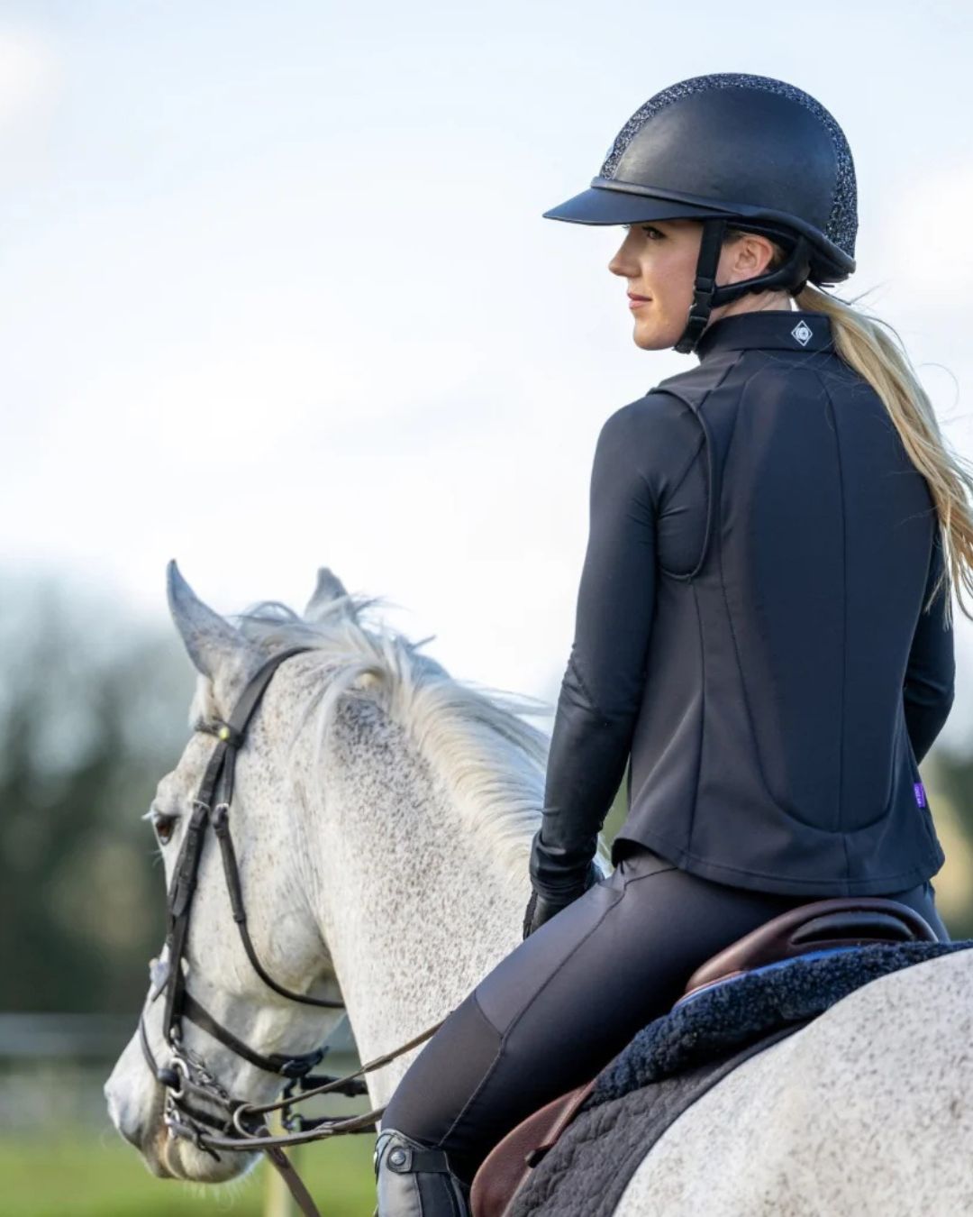 Person riding a horse wearing equestrian attire with Charles Owen Eclipse Back Protector  with a blurred background | Malvern Saddlery