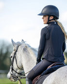 Person riding a horse wearing equestrian attire with Charles Owen Eclipse Back Protector  with a blurred background | Malvern Saddlery