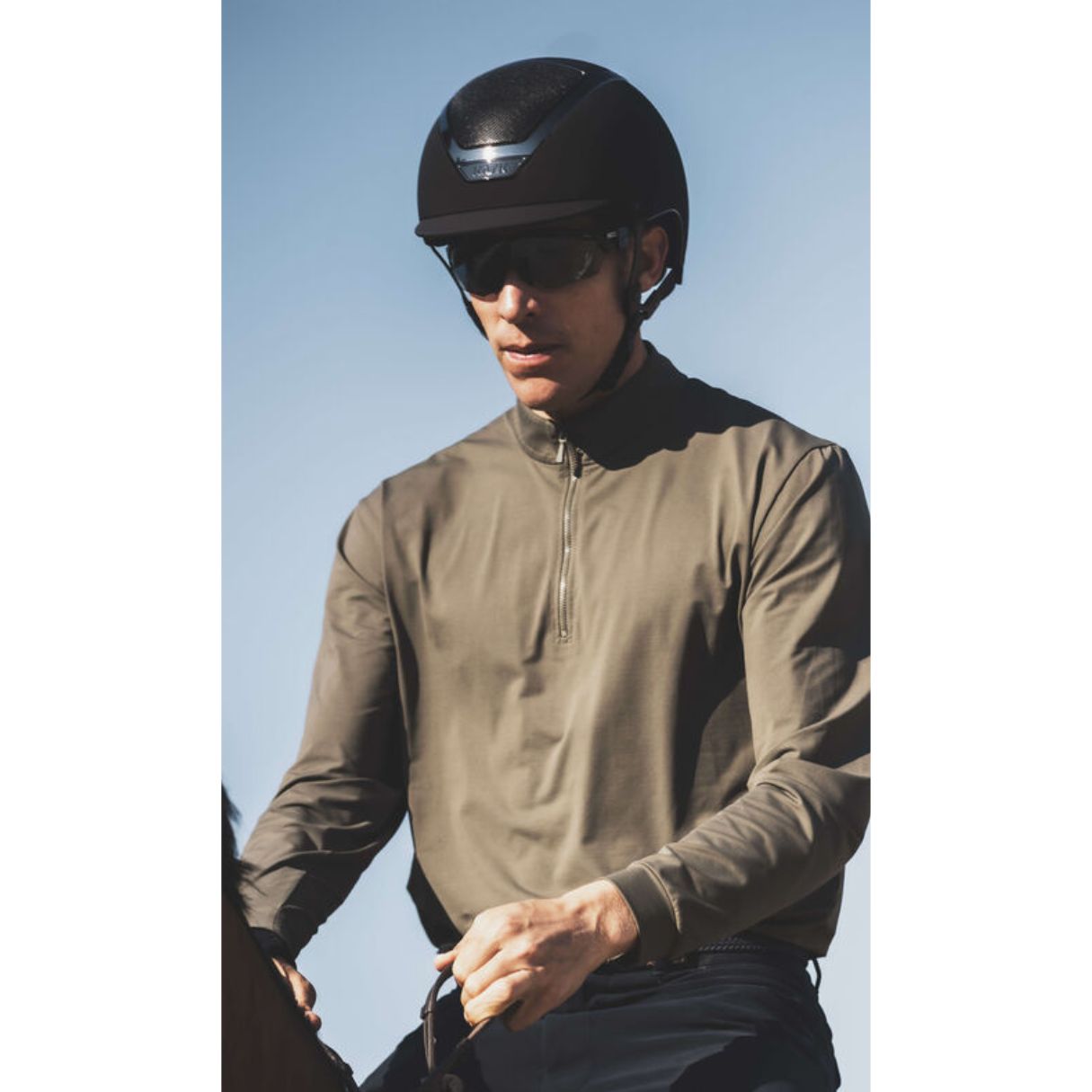 Kask Dogma Chrome Equestrian Helmet - Black; shown on rider wearing sunglasses with sky background| Malvern Saddlery