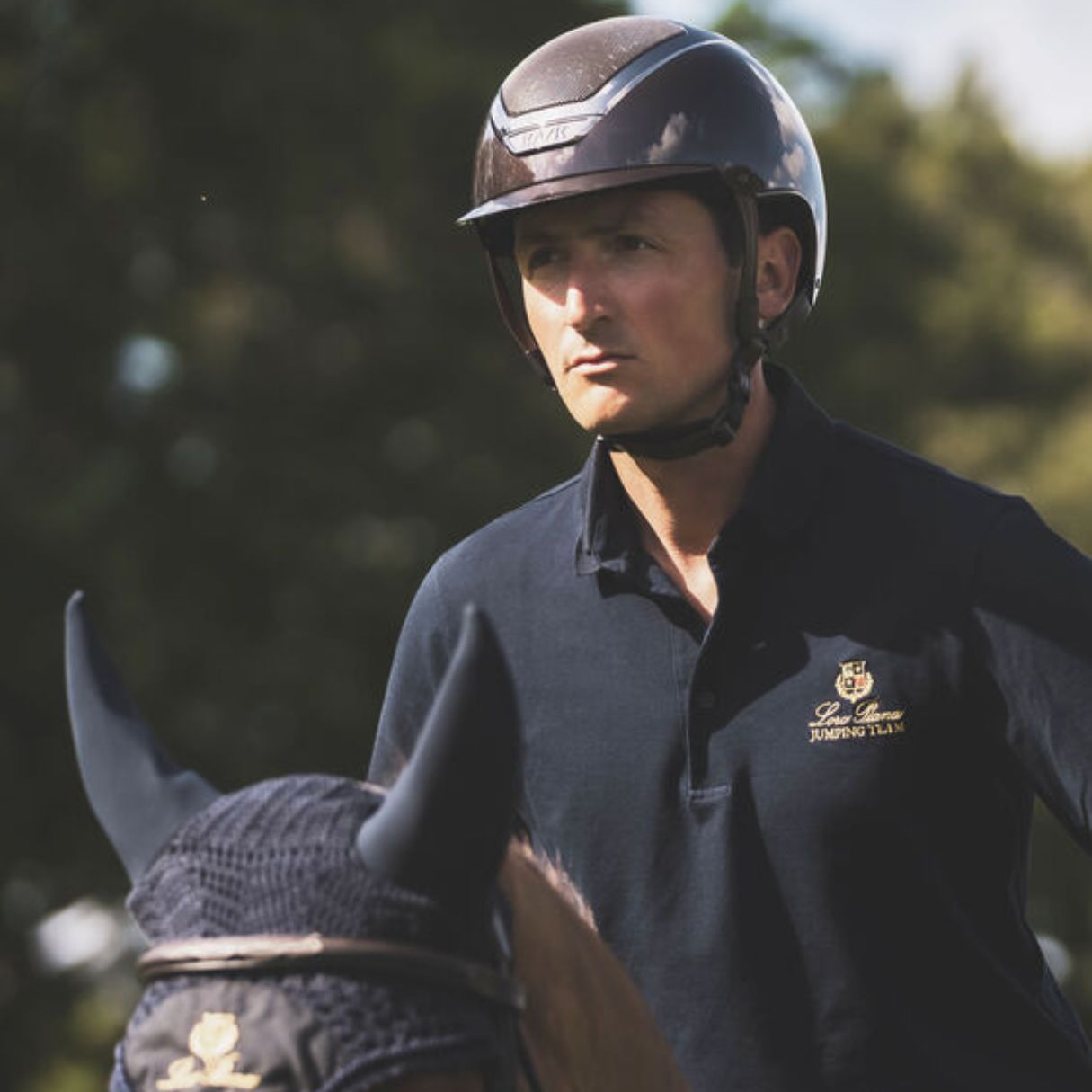 Kask Equestrian Dogma Pure Shine Helmet - Espresso Brown; shown on rider on horse with trees in background | Standard Brim Helmets | Malvern Saddlery
