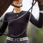 Ellany Elastic Belt with Stirrup Buckle - Harlow pattern, with gunmetal buckle shown on Woman in equestrian attire holding a horse's bridle with a blurred natural background | Malvern Saddlery