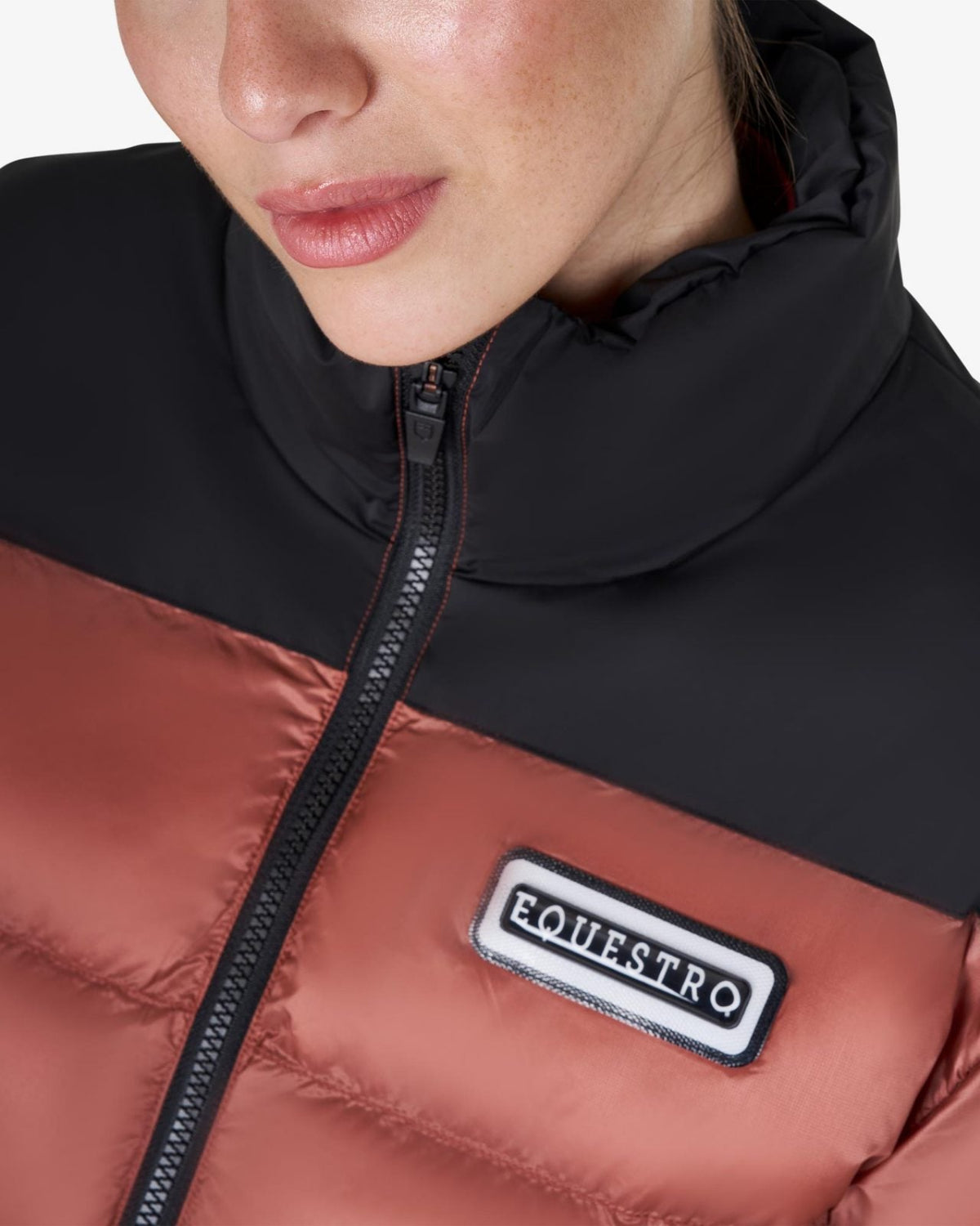 Equestro Cropped Puffer Jacket - Redwood & Black; chest logo detail, shown on woman on white background | Ladies Outerwear | Malvern Saddlery
