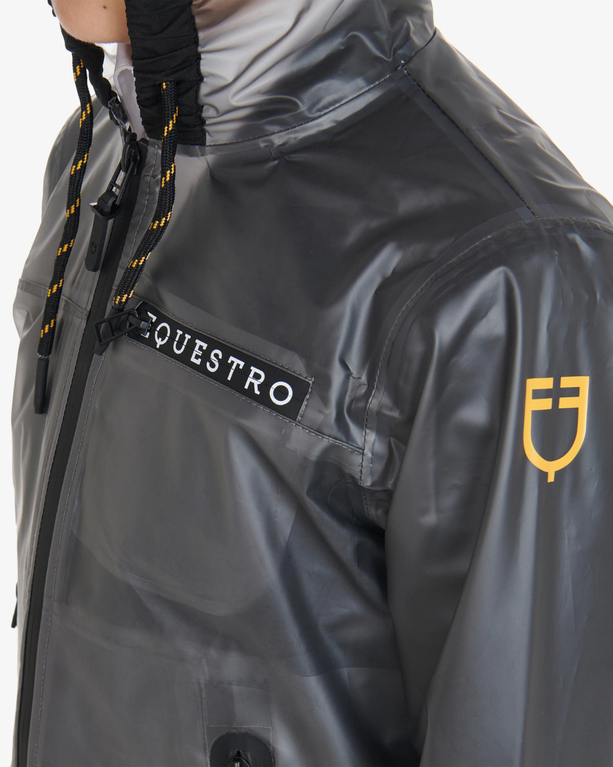 Equestro Young Rider Unisex Raincoat - shown on person, detail view of yellow logo on left arm  | Children's Riding Apparel | Malvern Saddlery