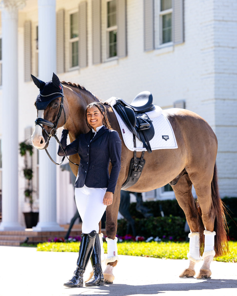 LeMieux Puissance Suede Dressage Saddle Pad - White, shown on horse standing next to woman in equestrian attire | Malvern Saddlery