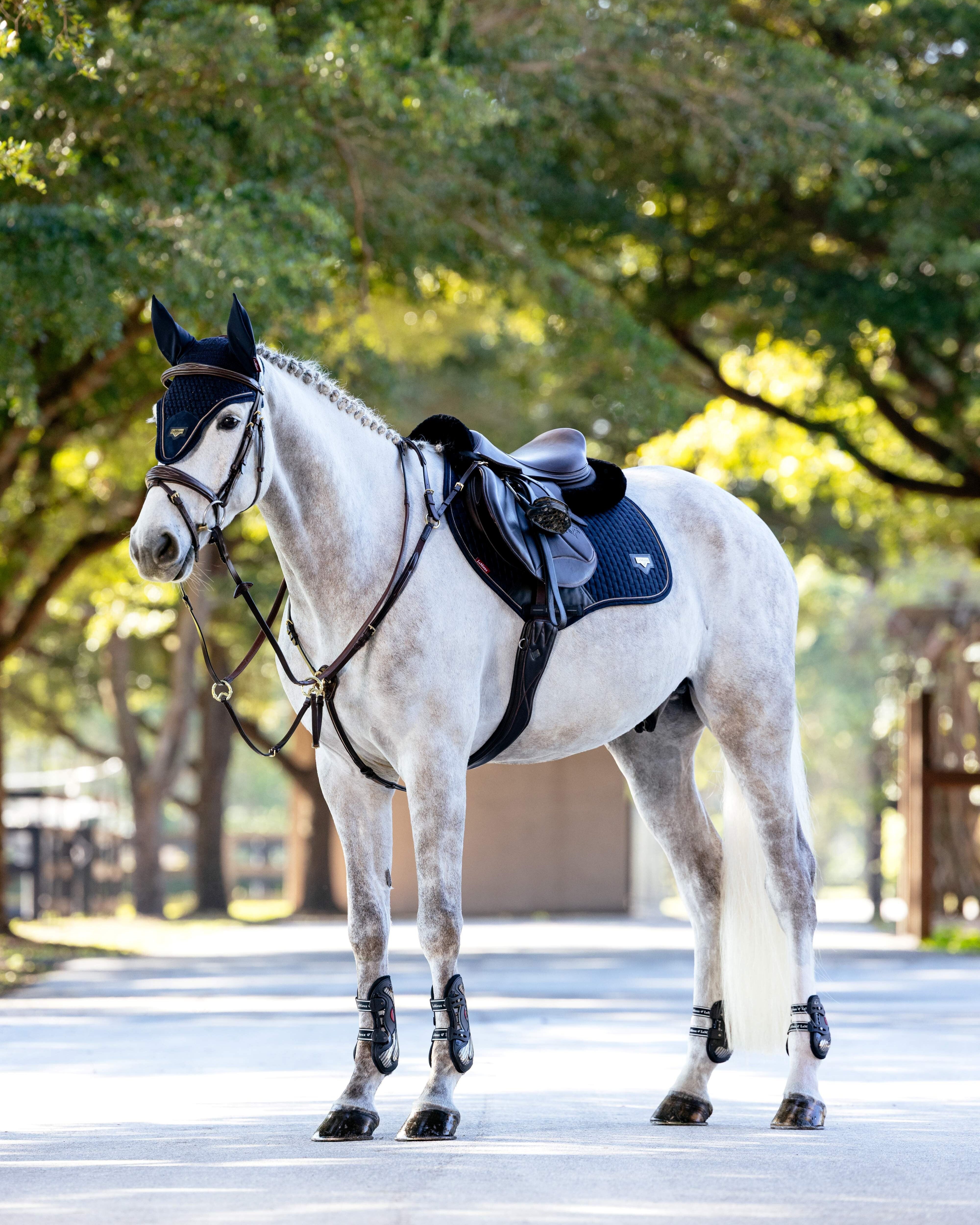 LeMieux Puissance Close Contact Saddle Pad - Navy - shown on dapple gray horse with additional tack, trees in background | Jumper Saddle Pads | Malvern Saddlery