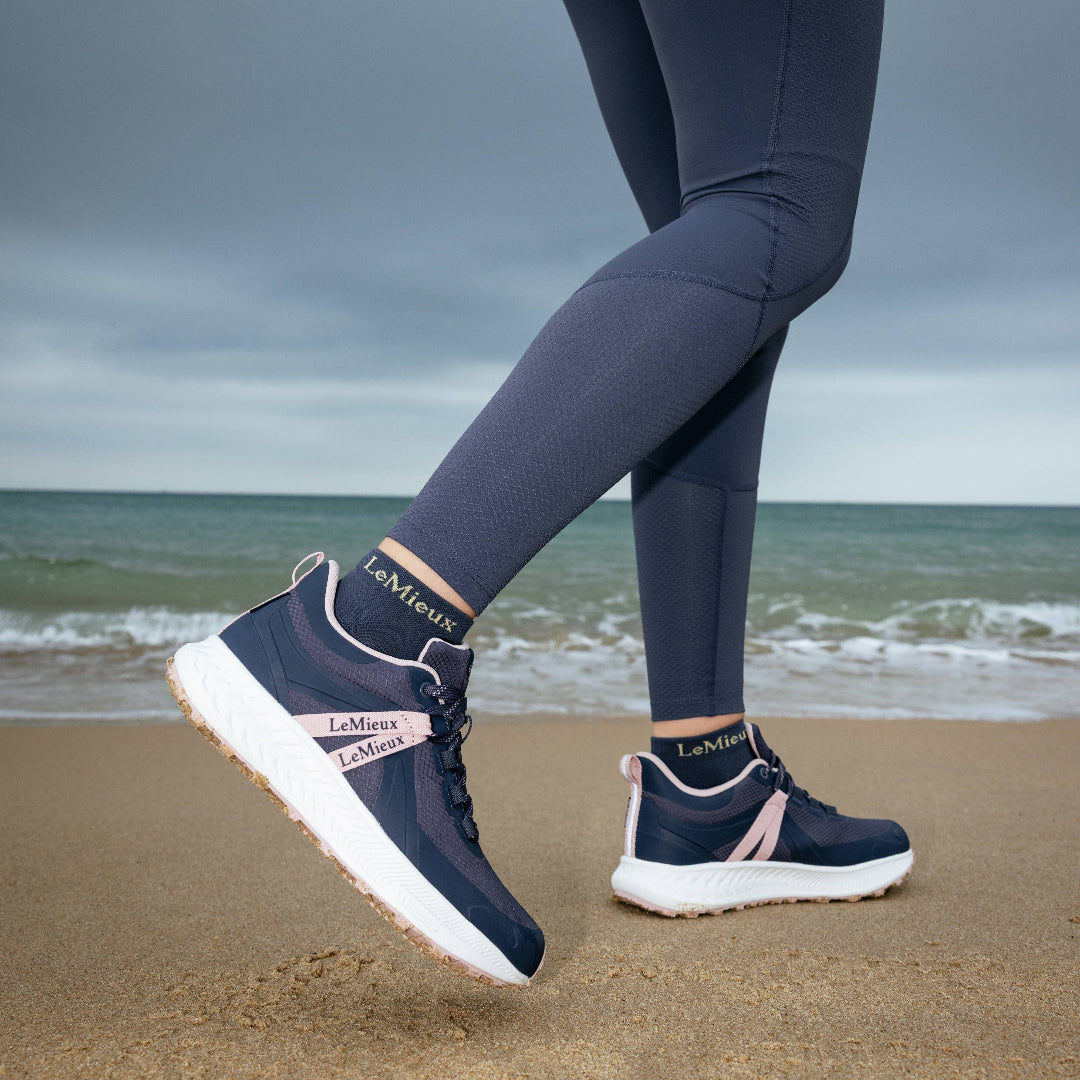 LeMieux Trax Viva Waterproof Sneaker - Navy/Pink, shown on person walking on beach | Malvern Saddlery