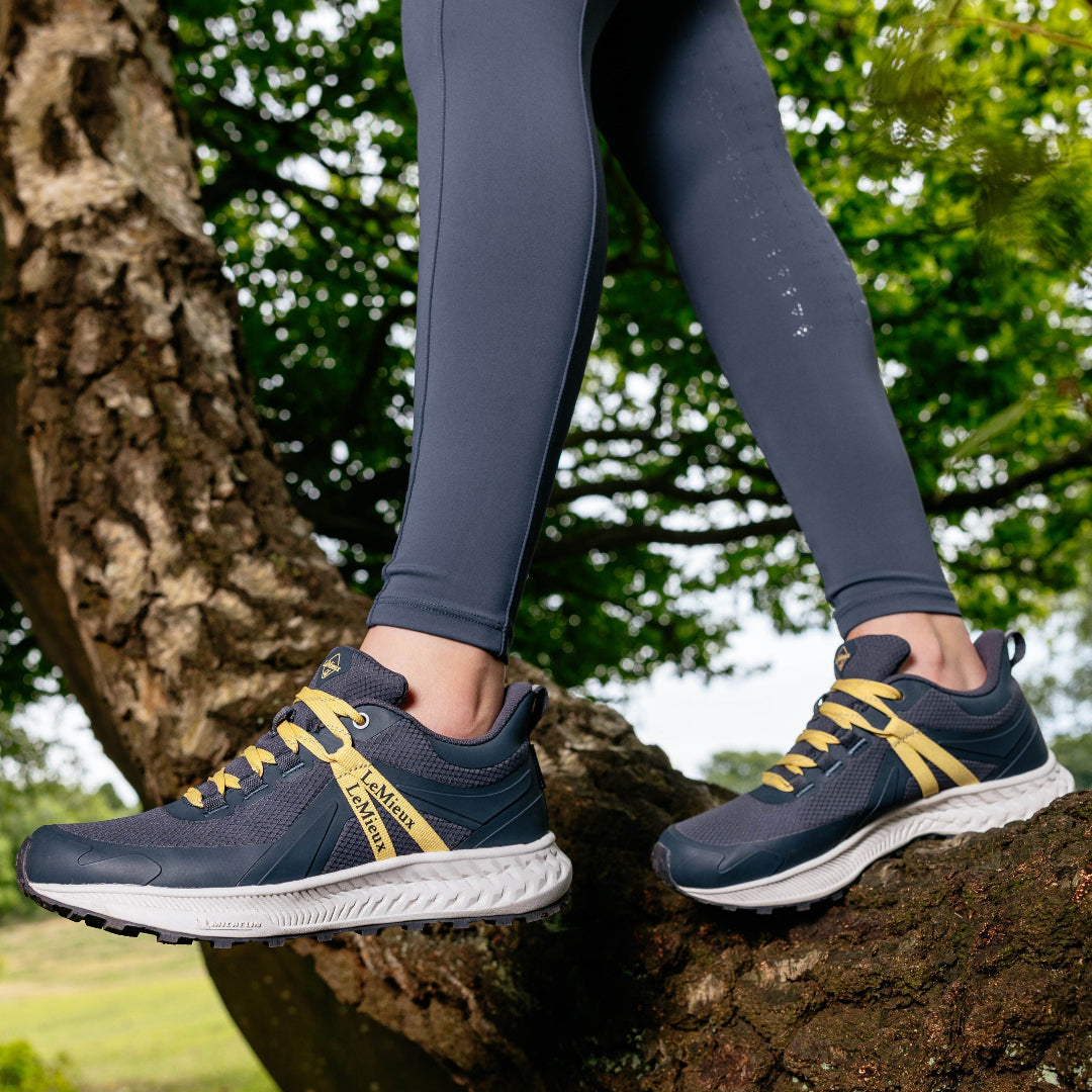LeMieux Youth Trax Viva Waterproof Sneaker - Dusk, shown on person standing on tree trunk | Malvern Saddlery