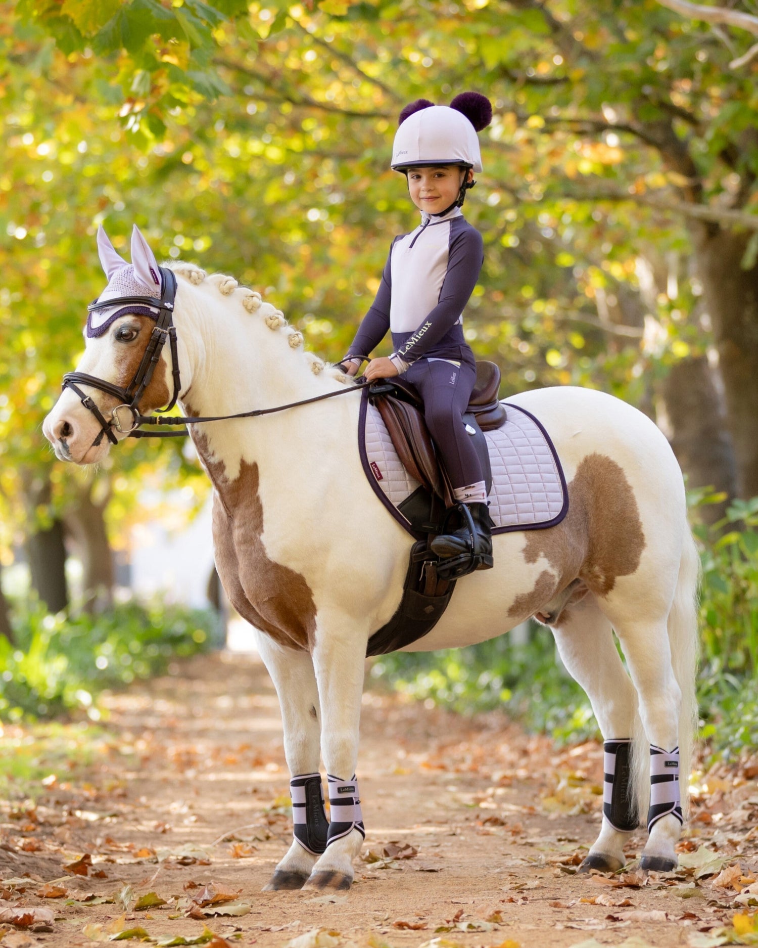 LeMieux Mini Base Layer Top - Lilac, shown on young girl on horse on bridle path | Children's Riding Apparel | Malvern Saddlery