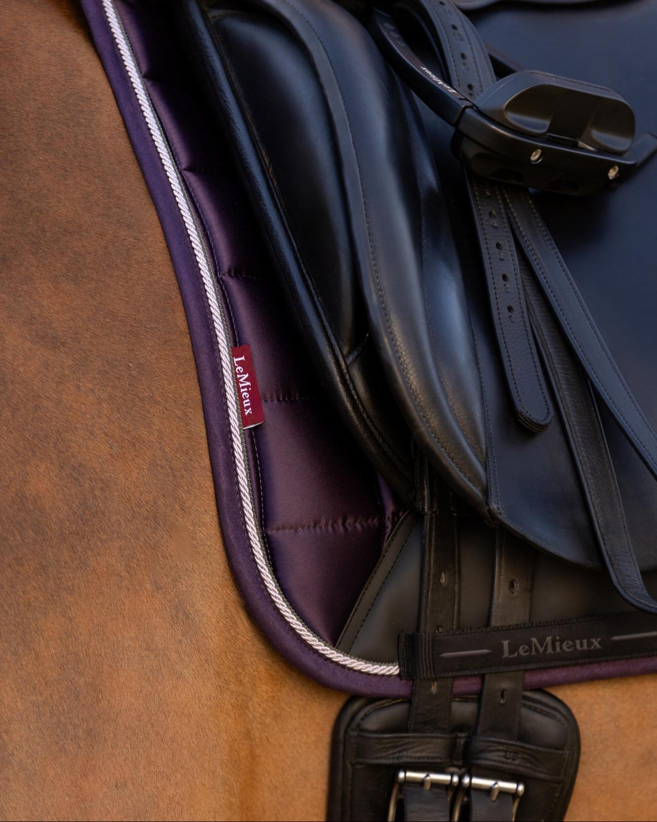 LeMieux Merino+ Loire Classic Dressage Square Saddle Pad - Juniper Purple with Black, close up of girth tabs shown on horse with black saddle blurred trees in background | Malvern Saddlery