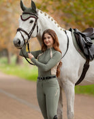 LeMieux Philippa Mesh Ladies Base Layer Top - Rosemary Green, shown on woman standing with white horse  | Athletic Wear | Malvern Saddlery