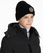 Person wearing LeMieux Bodie black beanie with a logo and a black coat on a white background | Malvern Saddlery