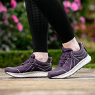 LeMieux Trax Viva Waterproof Sneakers - Juniper Purple; shown on person wearing black leggings with blurred outdoor background | Malvern Saddlery