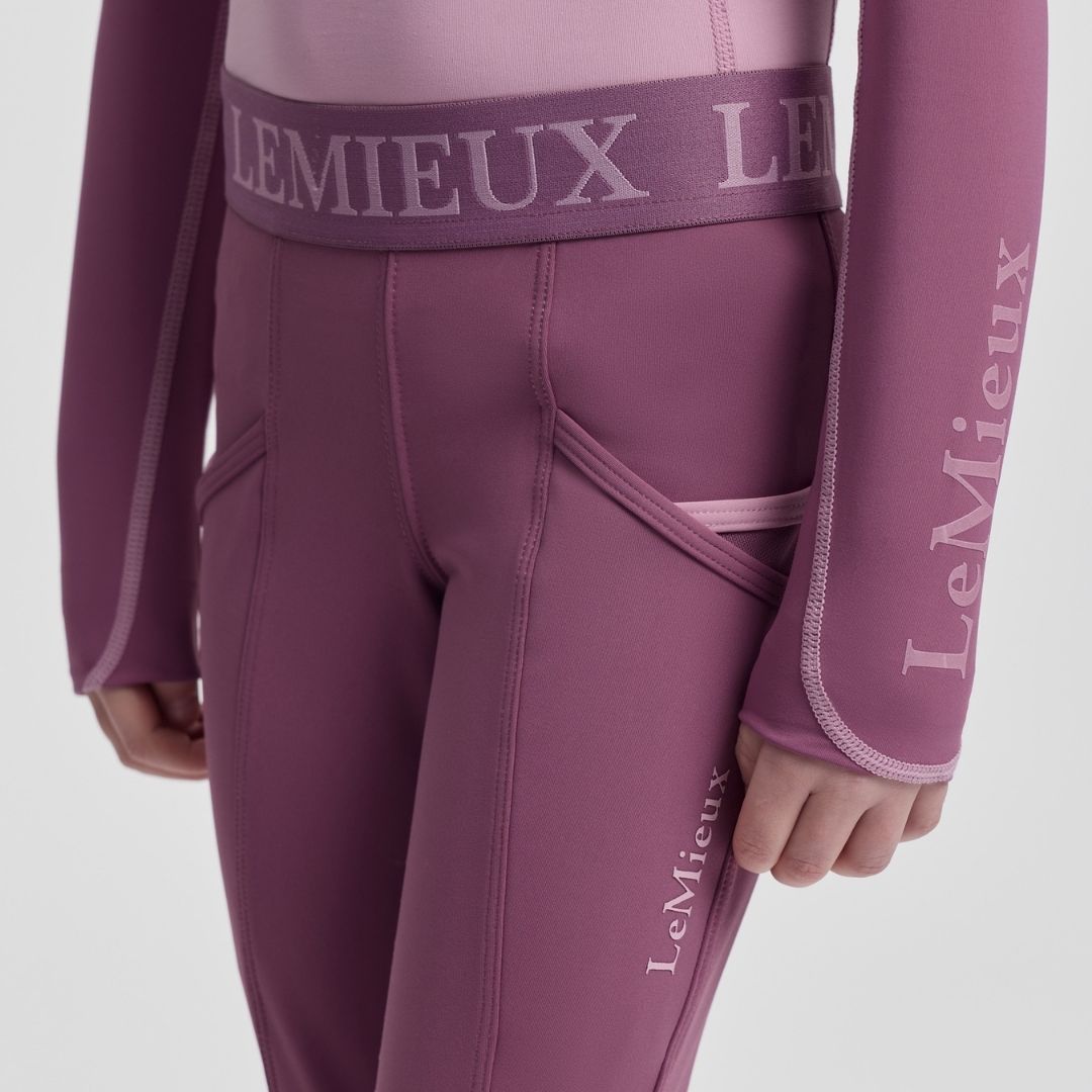 LeMieux Mini Pull On Breech - Mallow Pink; close up of waist & pockets model, gray background | Malvern Saddlery