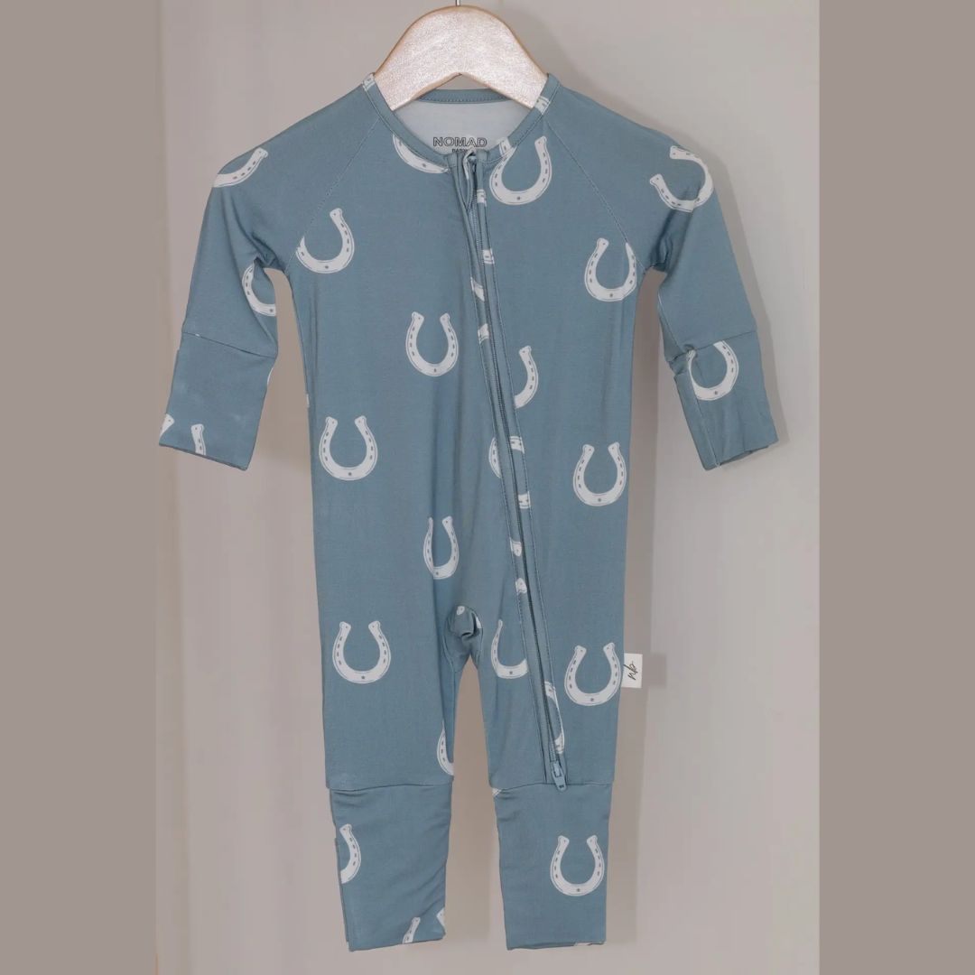 Blue baby onesie with white horse shoe pattern on a hanger against a gray background | Malvern Saddlery