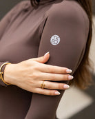 TKEQ CHLOE High Collar Technical Top - Espresso Brown, on model, close up showing logo on left arm | Riding Apparel | Malvern Saddlery