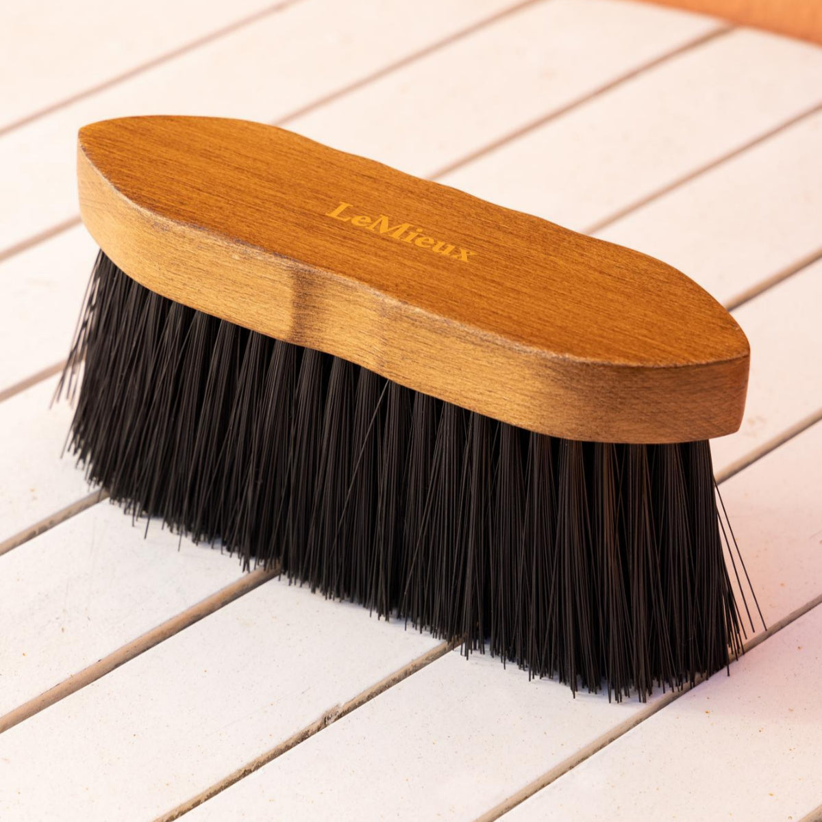 LeMieux Artisan Flick Horse Brush - Brown with Black bristles; shown on white slatted table | Horse Grooming | Malvern Saddlery