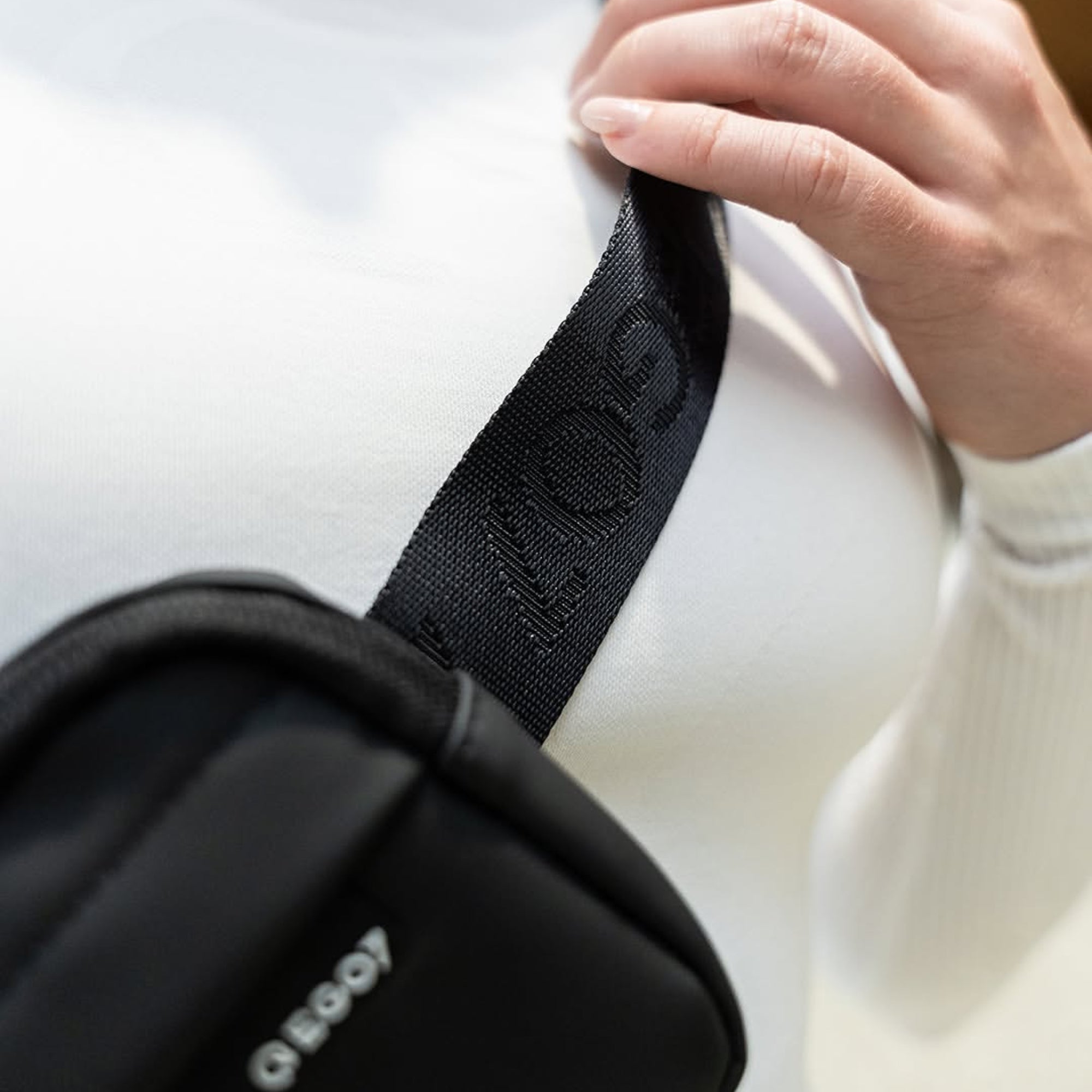 Close-up view of a rider wearing the black EGO7 Agnes Pouch cross-body over a white top, highlighting the branded strap and micro-injected EGO7 logo