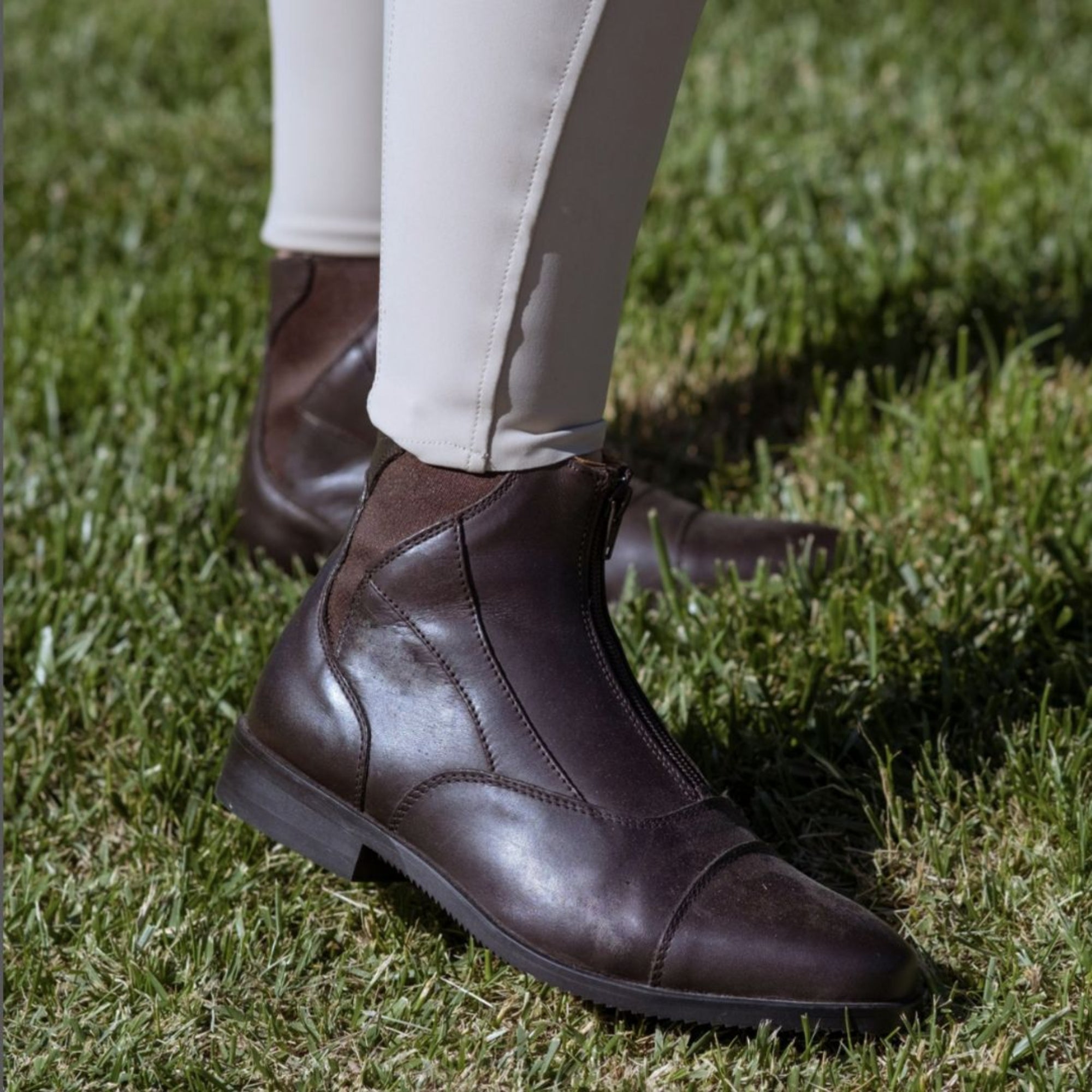 EGO7 Taurus brown front-zip leather equestrian paddock boots worn with beige riding breeches on grass, side profile view