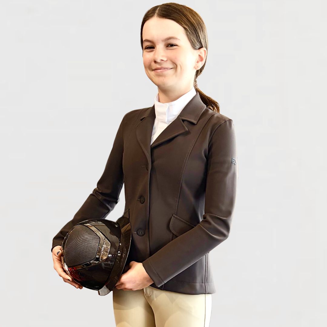 For Horses Winx Hunter Girls Show Jacket - Brown; shown on young rider holding Kask Helmet | Young Rider Competition Clothing | Malvern Saddlery