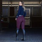 Halter Ego Evolution Ladies Mid Rise Full Grip Breeches - Merlot with Dark Blue piping & logo, shown on woman in barn wearing riding boots and blue top | Malvern Saddlery