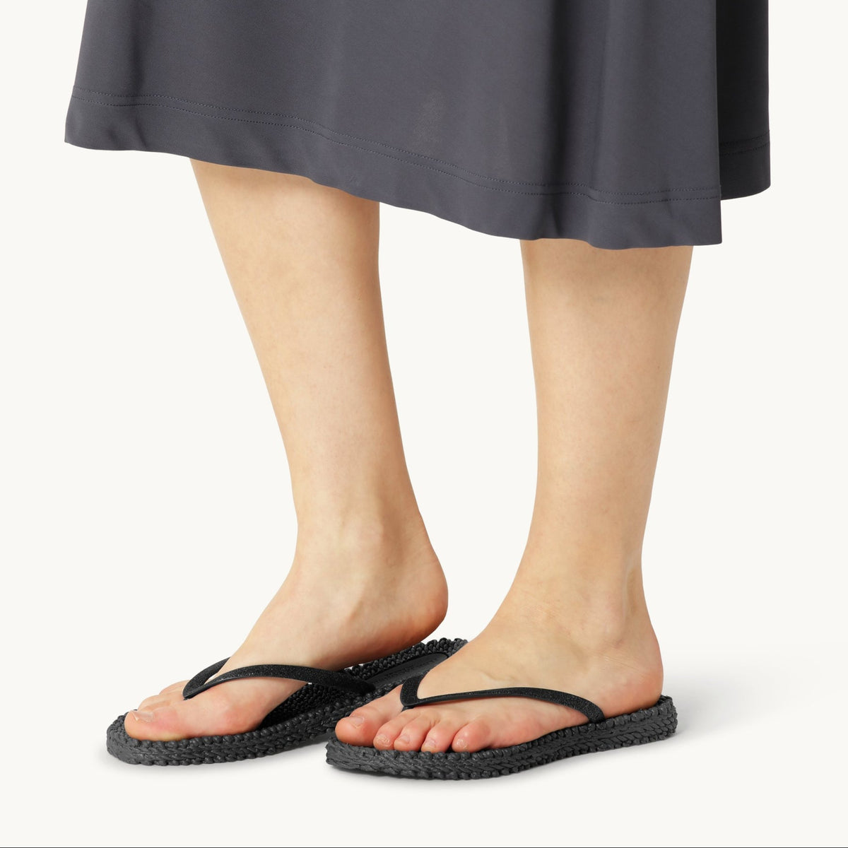 Woman wearing Ilse Jacobsen Cheerful black glitter flip flops at Malvern Saddlery featuring a textured massaging footbed