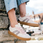 LeMieux Stockbridge Suede Lifestyle Trainers - Stone; shown on woman sitting on stone wall | Casual Footwear | Malvern Saddlery