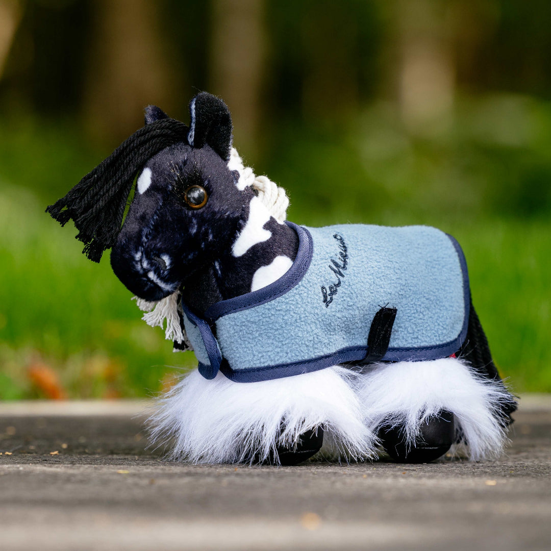 LeMieux Tiny Pony - Razzle, shown with blue fleece cooler with blurred green woods background | Children's Toys | Malvern Saddlery