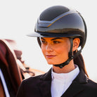 KASK Star Lady Pure Shine Equestrian Helmet - Anthracite Gray; close up lifestyle image shown on woman next to horse | English Riding Helmets | Malvern Saddlery