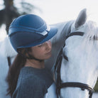 KASK Star Lady Pure Shine Equestrian Helmet - Atlantic Blue; close up lifestyle image worn by woman with white horse | English Riding Helmets | Malvern Saddlery