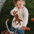 Baby Toddler Gwenny Horse Sweater; shown on toddler riding tricycle | Equestrian Gifts | Malvern Saddlery