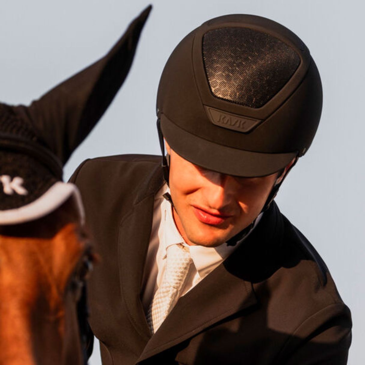 KASK Equestrian Dogma Hunter Helmet - Black; close up shown on rider wearing showcoat on horse | Malvern Saddlery