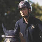 Kask Equestrian Dogma Pure Shine Helmet - Espresso Brown; shown on rider on horse with trees in background | Standard Brim Helmets | Malvern Saddlery