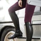 Rider wearing EGO7 Aries black leather dress riding boots with burgundy breeches on horse trailer steps, showing the tall boot fit and E-Tex grip panel.
