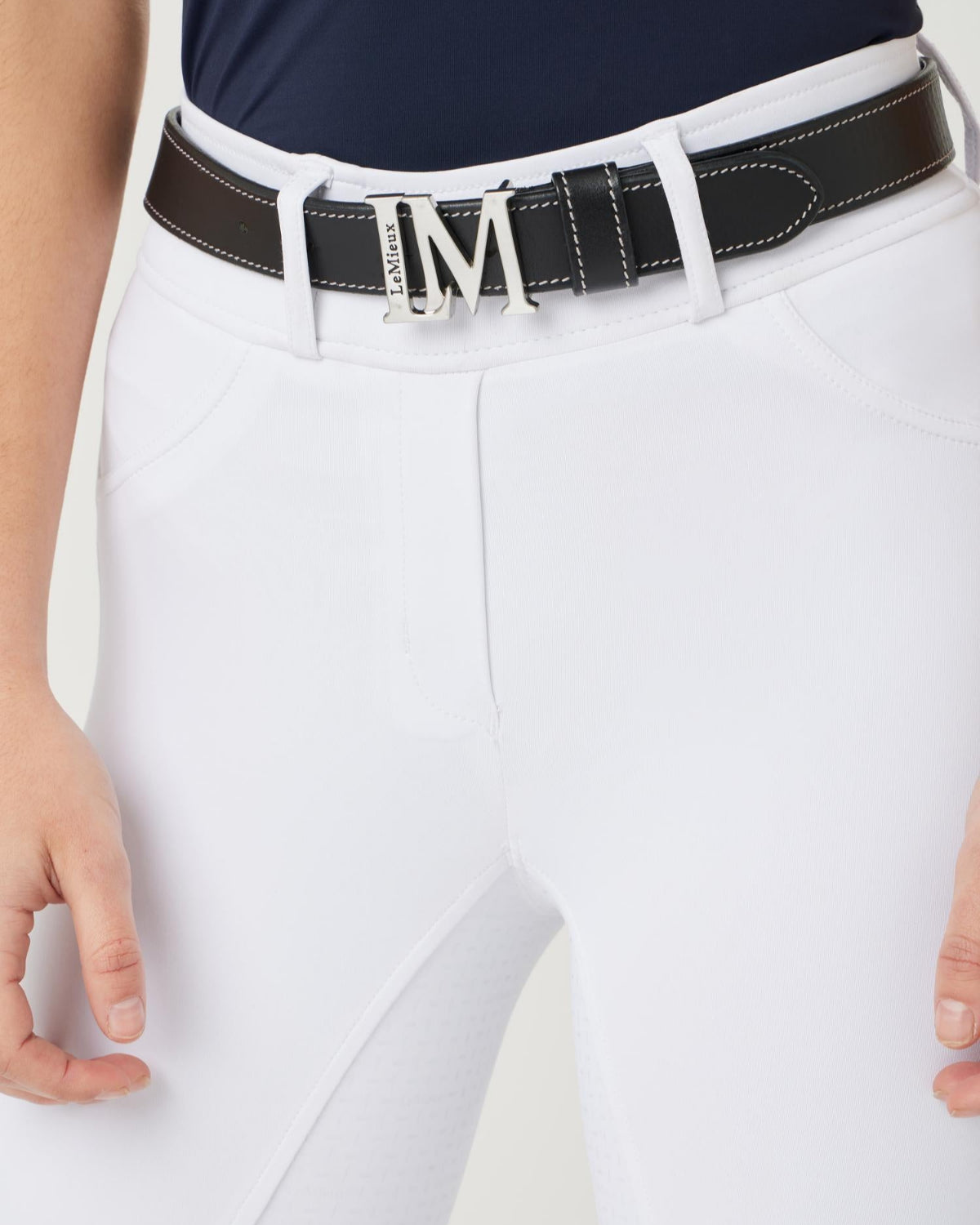 LeMieux Monogram Leather Belt - Black; detail shown on woman wearing white breeches | Malvern Saddlery