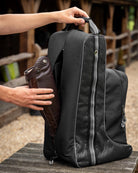 LeMieux Elite Pro Helmet & Boot Bag - Black, shown with person removing boot from back of bag | Equestrian Accessories | Malvern Saddlery