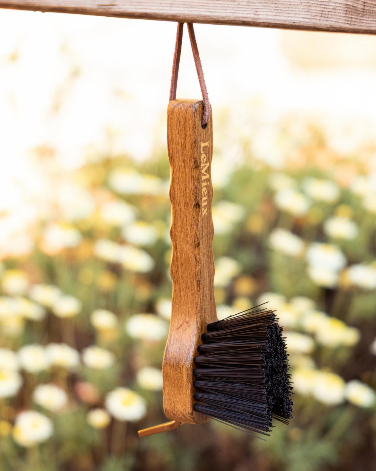 LeMieux Artisan Hoof Pick - shown hanging from hook, blurred flowers in background | Hoof Care | Malvern Saddlery