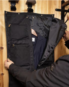 LeMieux Luxe Show Jacket Duffle Bag, shown on wood wall with blue competition jacket, person opening | Equestrian Travel Accessories | Malvern Saddlery