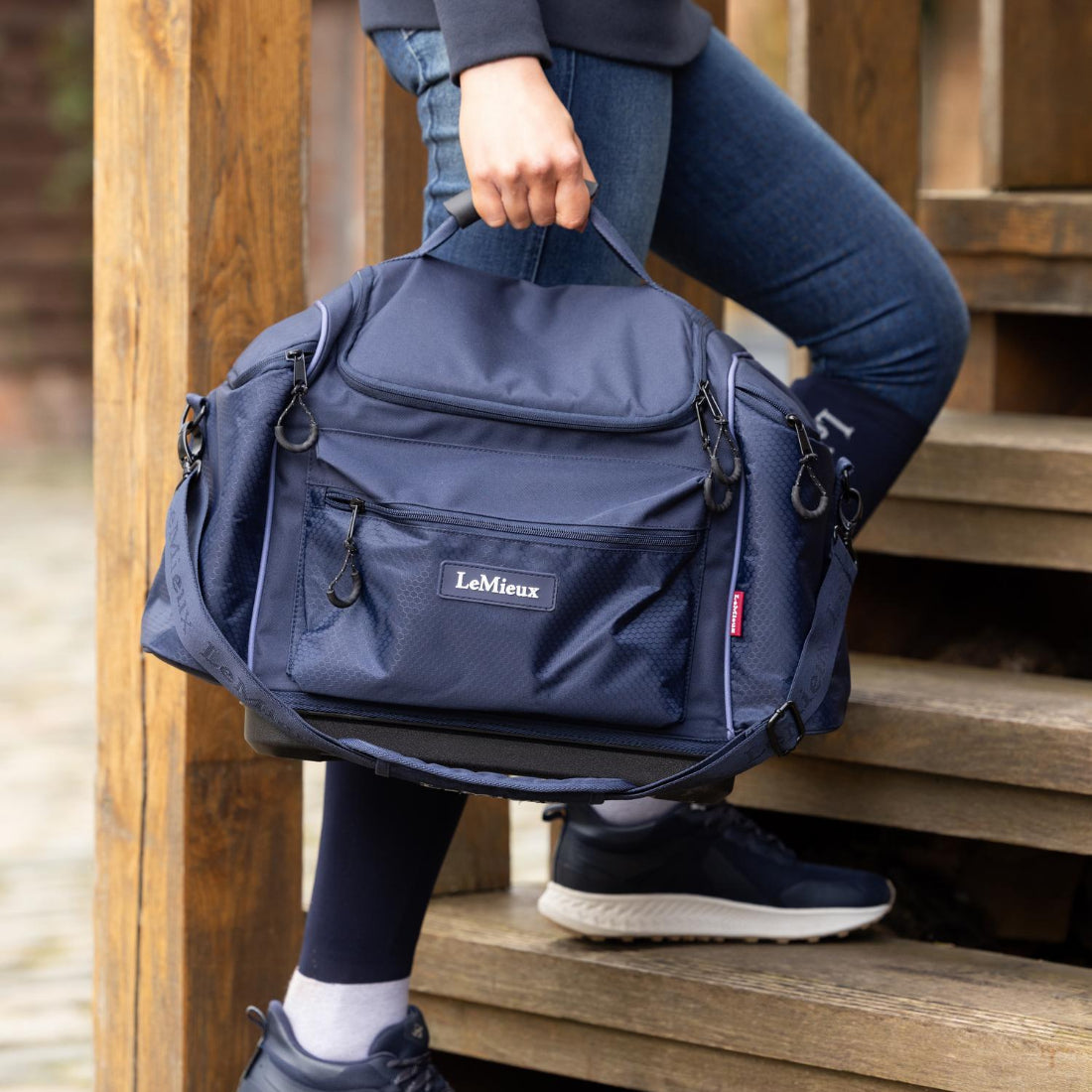 LeMieux Grooming Kit Pro Bag - navy; held by handle lower body of person going up steps | Malvern Saddlery