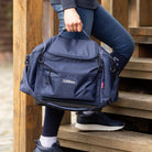 LeMieux Grooming Kit Pro Bag - navy; held by handle lower body of person going up steps | Malvern Saddlery