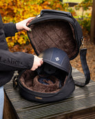 LeMieux Luxe Hat/Helmet Box - Black  with Brown faux fur lining, shown with person putting helmet into case | Rider Travel Accessories | Malvern Saddlery
