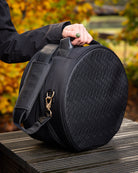LeMieux Luxe Hat/Helmet Box - Black , shown outdoors on table with trees in background woman's hand on handle | Rider Travel Accessories | Malvern Saddlery