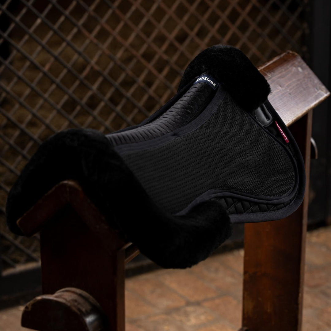 LeMieux Streamline Half Pad - Black/Black; shown on saddle rack with brown lattice wall background  | Equestrian Correction Pads | Malvern Saddlery